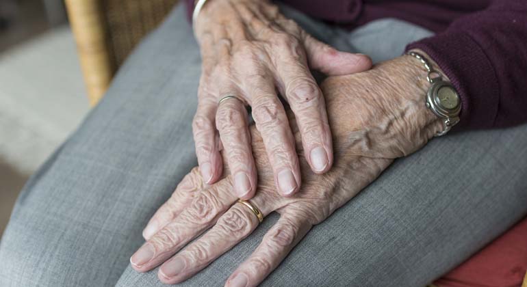 En äldre kvinnas händer som ligger i hennes knä