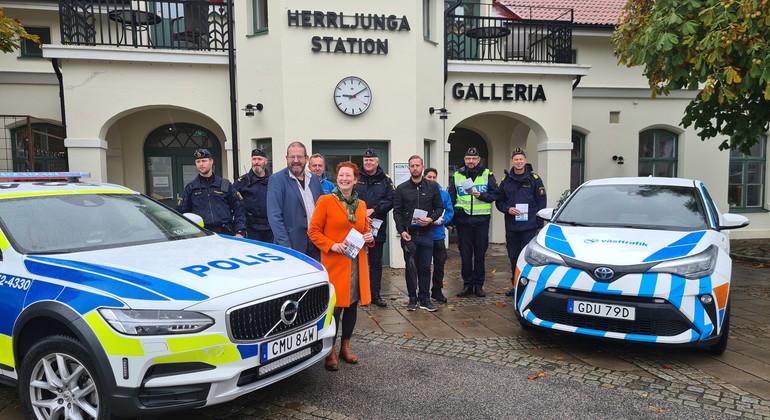 Personer som står och poserar framför stationshuset i Herrljunga. Bil från polisen och Västtrafik syns också i bilden. 