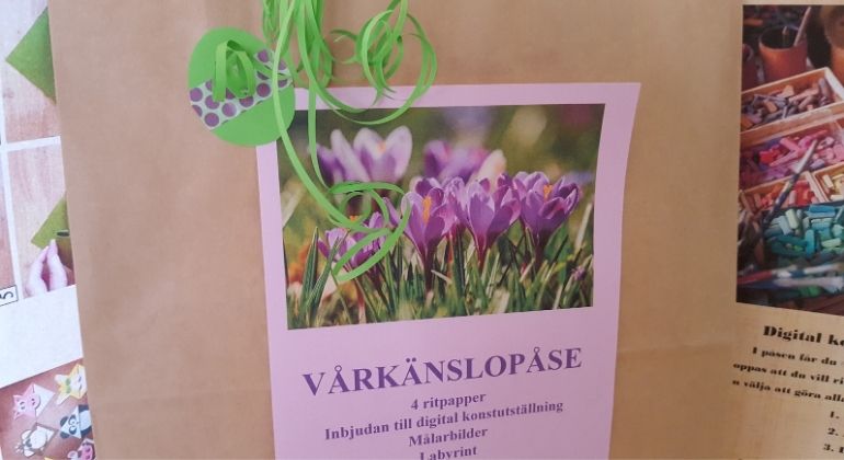 En papperspåse dekorerad med ett grönt påskägg och en bild med lila krokusar och med texten Vårkänslopåse.
