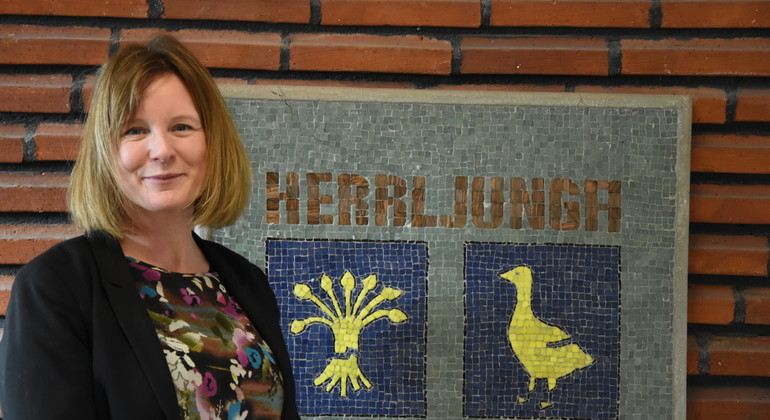 Rektor Linda Rogberg framför Herrljungas kommunvapen.