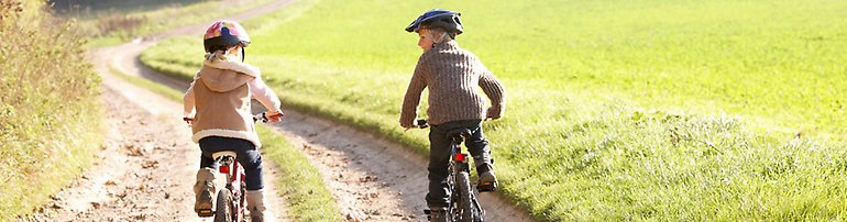 Två barn cyklar i naturen